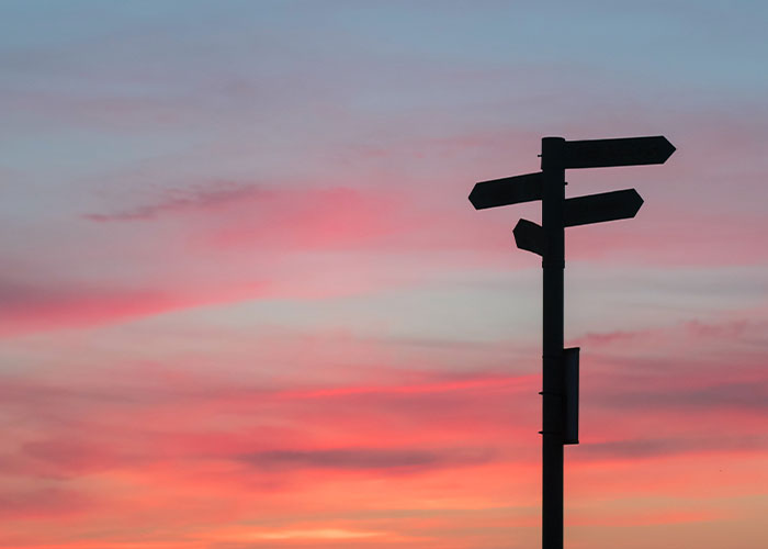 Silhouette of a waypost with a sunrise in the background
