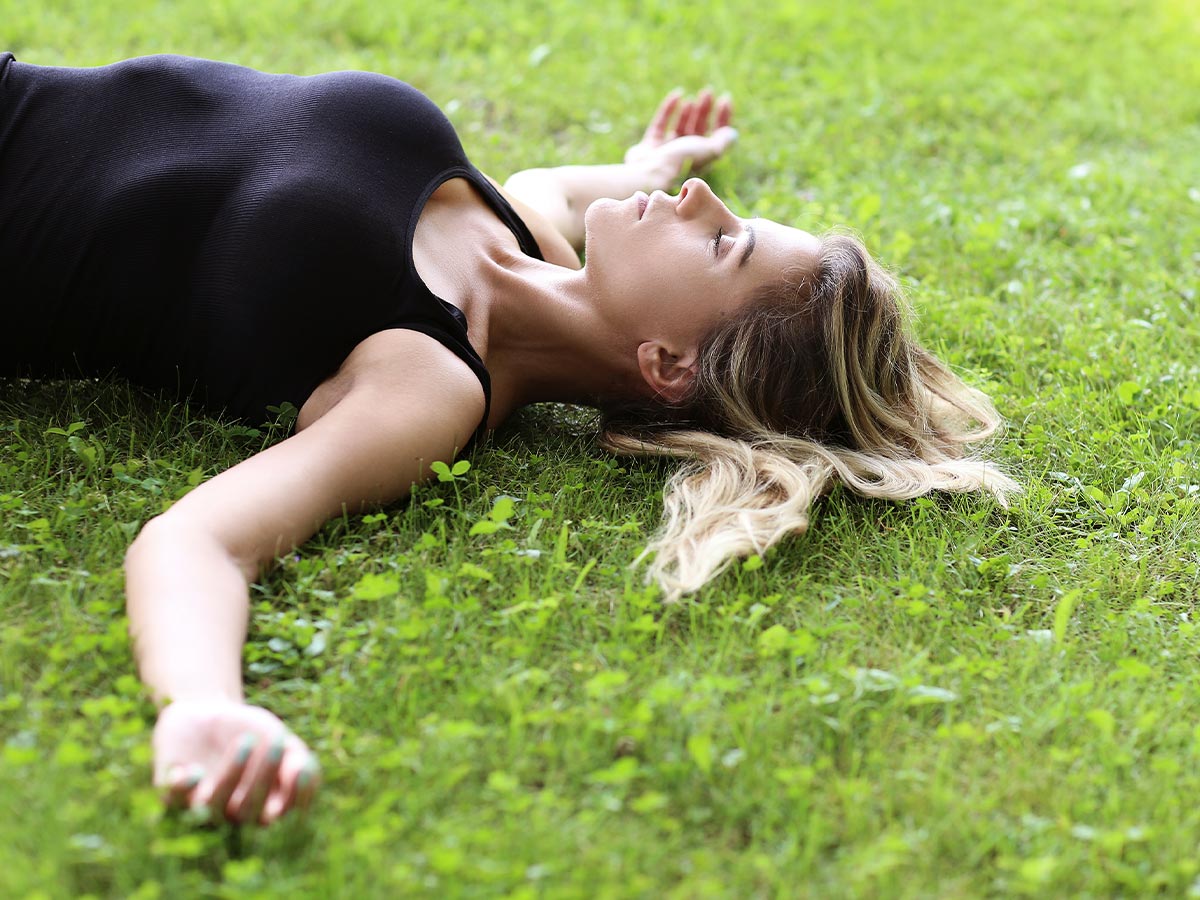 a woman deep breathing while laying outside